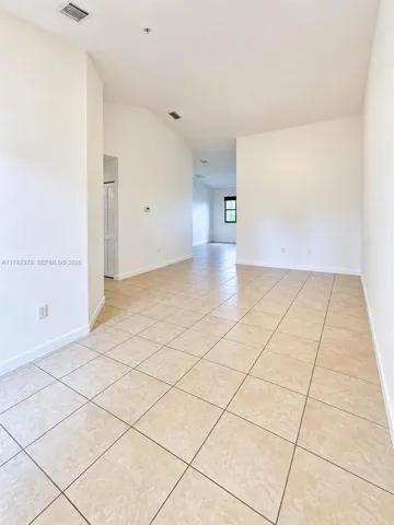 Open-concept interior featuring vaulted ceilings and neutral large-format tile flooring