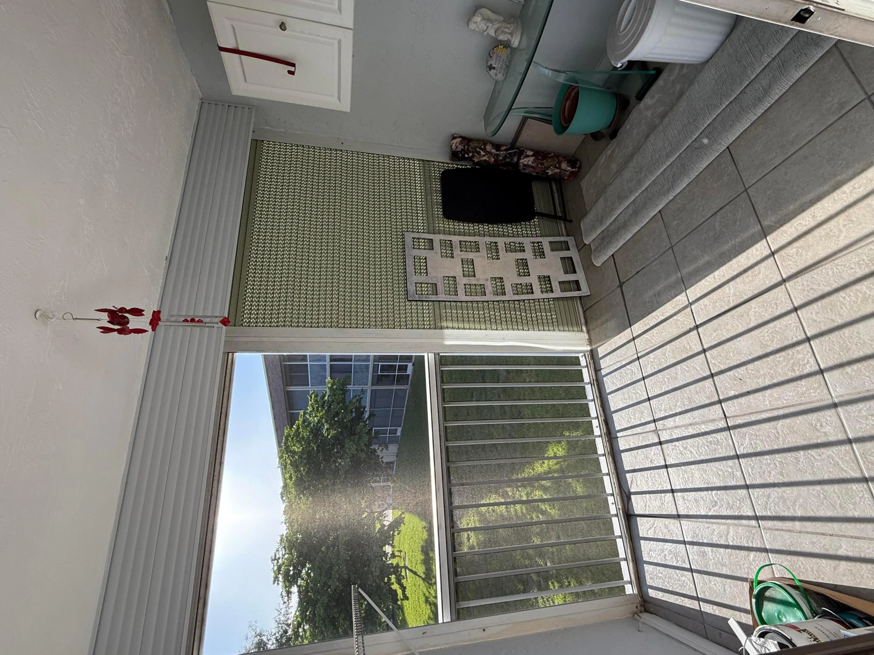 Enclosed balcony featuring a tiled floor, white railing, and a slatted privacy screen