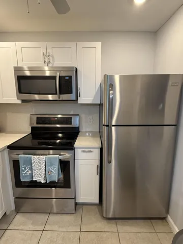 Modern kitchen featuring stainless steel appliances, white shaker-style cabinetry, and light-toned countertops