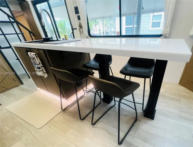 Rainfall verde kitchen sink with soap dispenser and Modern Quartz waterfall countertops with under-cabinet lighting.
