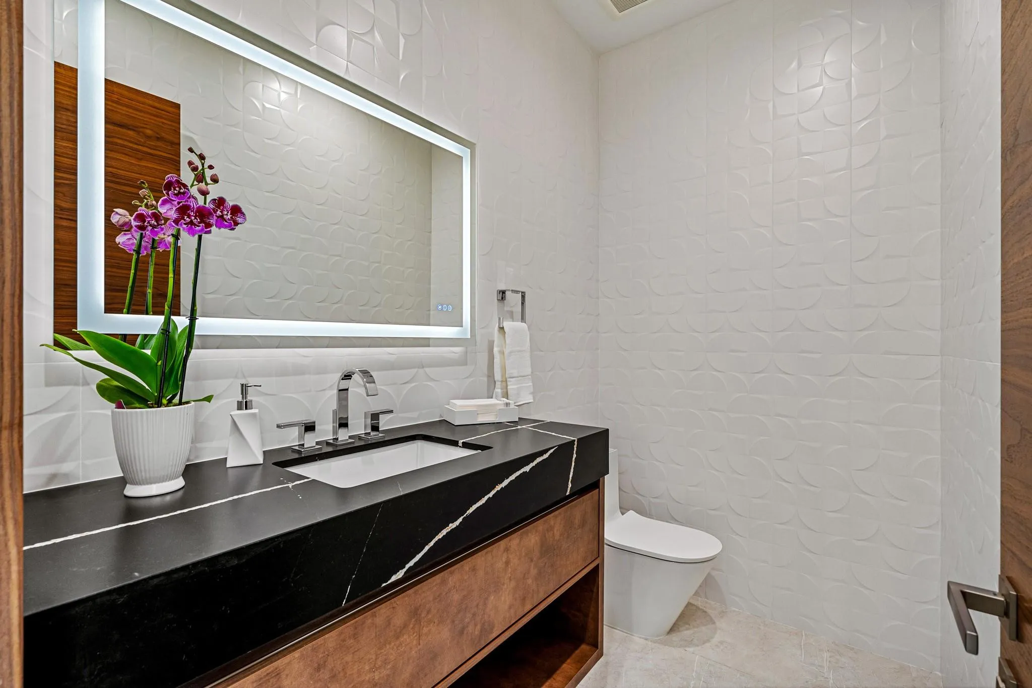 A sleek and stylish powder room featuring a floating vanity, bold contrasting finishes, and a clean, modern aesthetic. Thoughtfully designed, this refined space adds a touch of contemporary elegance for guests.