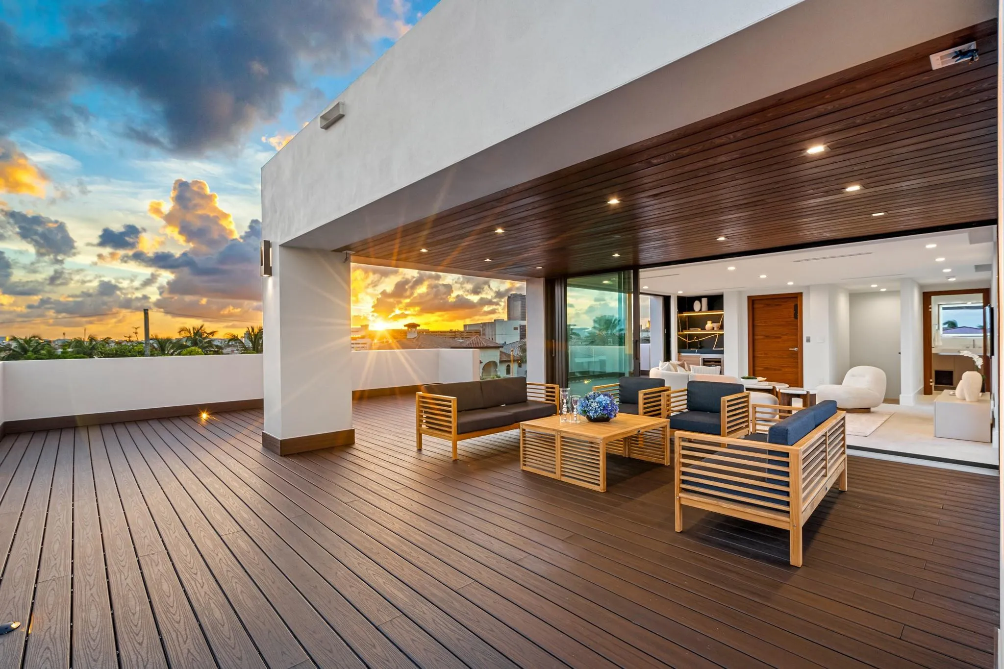 An expansive covered terrace featuring warm wood ceilings, elegant lounge seating, and seamless flow to the open-air deck beyond. Framed by breathtaking sunset skies, this sophisticated outdoor retreat is designed for elevated entertaining and relaxed coastal evenings.