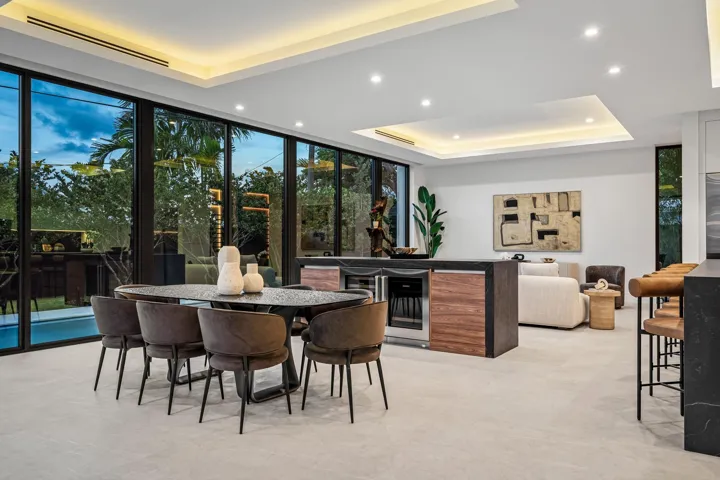A sophisticated dining space seamlessly integrated into the open-concept design, framed by floor-to-ceiling glass and tranquil garden views. Warm wood tones and clean contemporary lines create an inviting setting for refined indoor-outdoor entertaining.