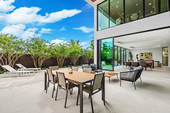 An expansive covered outdoor terrace designed for seamless entertaining, featuring a spacious dining area and comfortable lounge seating overlooking lush tropical landscaping. Modern and open, this inviting space extends the home’s living areas into a private resort-style setting.
