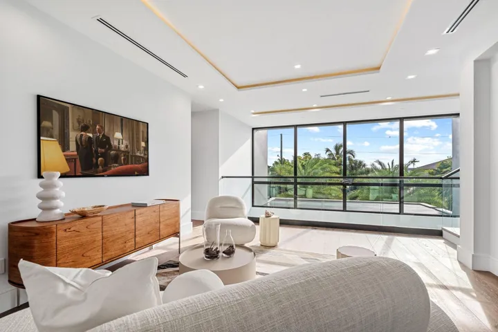 A serene waterfront bedroom showcasing clean modern lines, warm wood accents, and expansive windows framing tranquil water views. Bright and beautifully appointed, this private retreat blends contemporary elegance with a peaceful coastal backdrop.