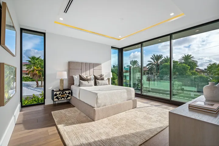 A bright and contemporary guest bedroom featuring floor-to-ceiling glass and direct access to a private balcony overlooking lush greenery. Airy and refined, this serene retreat offers guests their own elevated indoor-outdoor escape.