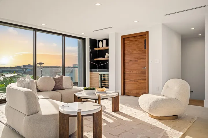 An elegant upper-level retreat featuring a private wet bar, warm wood accents, and expansive sliding glass doors opening to breathtaking water views. Sophisticated and serene, this refined lounge offers the perfect setting for elevated relaxation and sunset entertaining.