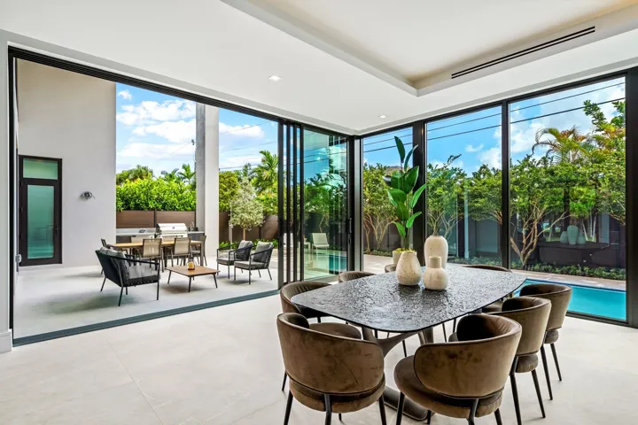 A light-filled dining area wrapped in floor-to-ceiling glass, offering seamless views of the lush garden and pool beyond. Modern and inviting, this elegant space is perfectly designed for effortless indoor-outdoor living and sophisticated entertaining.