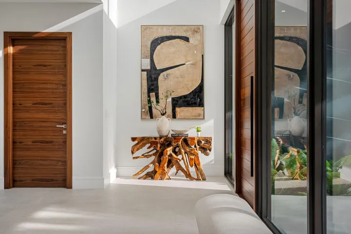 A refined entry vignette showcasing a rich wood front door, sleek glass panels, and curated modern artwork that sets an elegant first impression. Clean lines and warm textures create a welcoming yet sophisticated arrival experience.