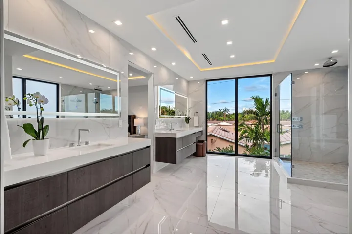 An expansive, light-filled bath retreat featuring dual floating vanities, a sleek glass-enclosed shower, and refined contemporary finishes throughout. Seamlessly connected to a private terrace, this spa-inspired space offers tranquil views and effortless indoor-outdoor luxury.