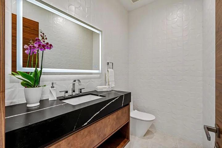 A sleek and stylish powder room featuring a floating vanity, bold contrasting finishes, and a clean, modern aesthetic. Thoughtfully designed, this refined space adds a touch of contemporary elegance for guests.