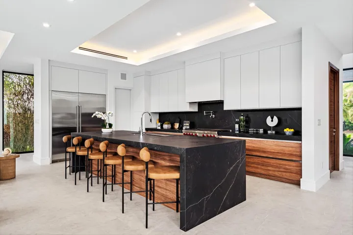 A showstopping chef’s kitchen anchored by a dramatic waterfall-edge island, rich wood cabinetry, and sleek black stone accents. Expansive and impeccably designed, this contemporary culinary space is crafted for elevated entertaining and everyday luxury.