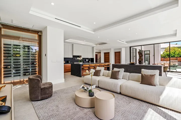 A refined open living area featuring clean architectural lines, custom millwork, and a seamless transition into the designer kitchen beyond. Bright and impeccably styled, this contemporary space is crafted for relaxed luxury and effortless entertaining.