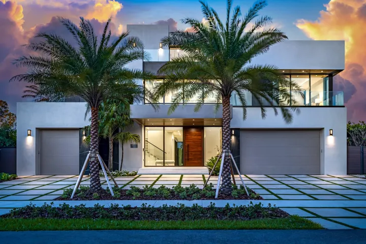 A striking modern façade framed by towering palms and clean architectural lines, illuminated beautifully at twilight. Sleek and sophisticated, this residence makes a bold statement with seamless indoor-outdoor flow and refined contemporary design.