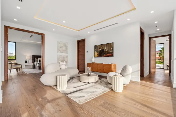 A spacious contemporary living area featuring warm wood floors, soft neutral tones, and clean architectural detailing throughout. Open and inviting, this refined space seamlessly connects to the adjoining suite for elevated comfort and modern elegance.
