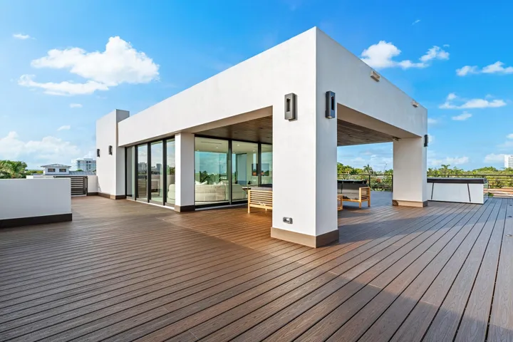 A striking rooftop-level pavilion set upon expansive wood decking, defined by clean architectural lines and floor-to-ceiling glass. Bold and contemporary, this elevated outdoor living space offers endless possibilities for sophisticated entertaining under open skies.