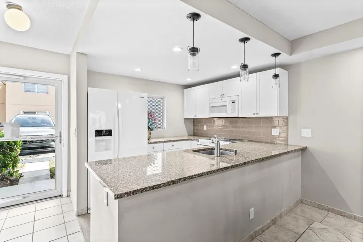 REMODELED, GROUND FLOOR END UNIT. Fabulous location near the beach, shopping, dining, airports and more! Modern kitchen with white shaker cabinetry, granite countertops and porcelain wood tile flooring. Open floorplan!