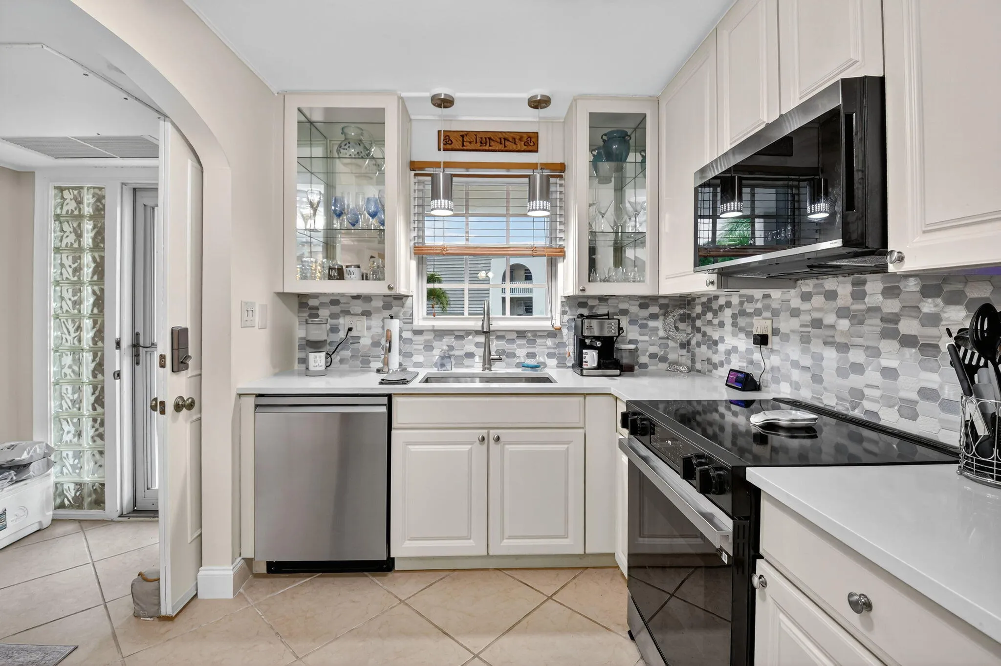 Neutral Cabinets and Counters w/stylish backsplash, pendant lighting and lighted glass cabinets
