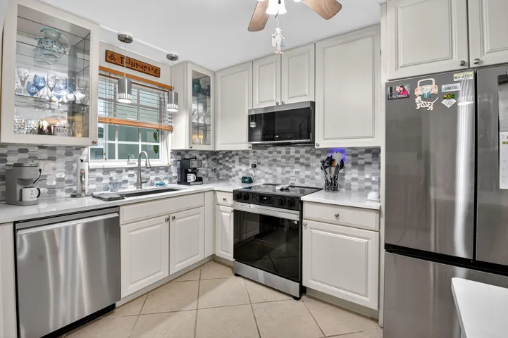 Neutral Cabinets and Counters w/stylish backsplash, pendant lighting and lighted glass cabinets