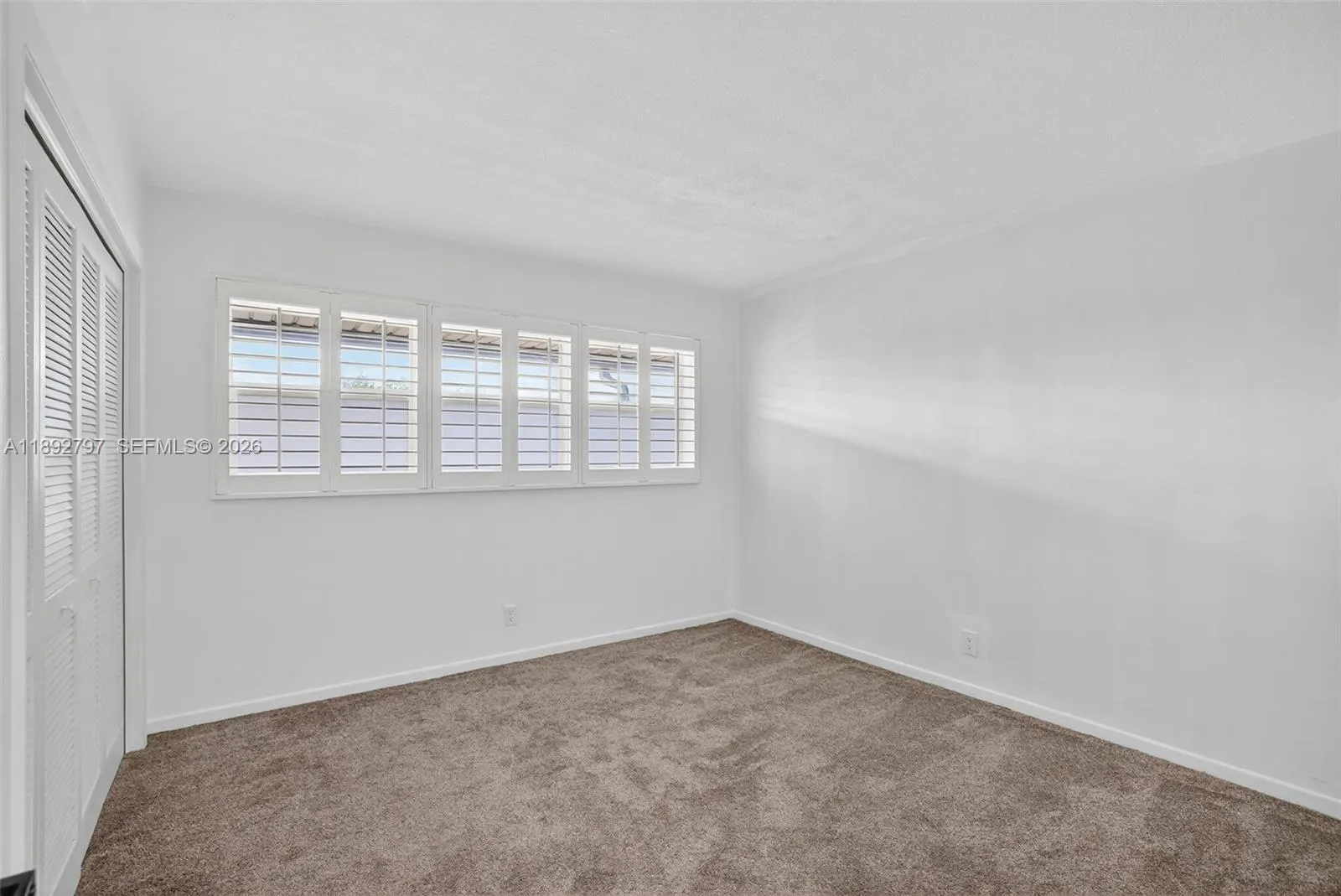 Large guest bedroom w/ louvered shutters / impact windows, upgraded carpt, and view to downtown from front windows
