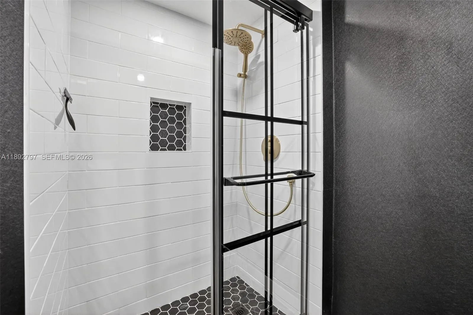 Super cool updated primary bathroom with glass shower enclosure, subway tile, handheld shower head, shampoo niche box