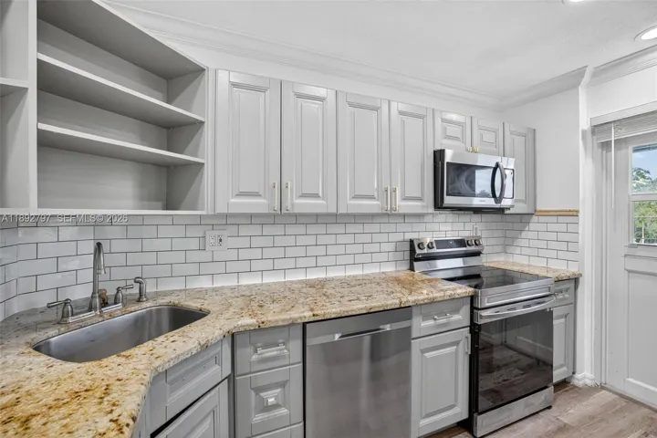 Open Concept Kitchen w/ newer stainless appliances, granite counter, updated cabinets and subway backsplash. Second door to catwalk