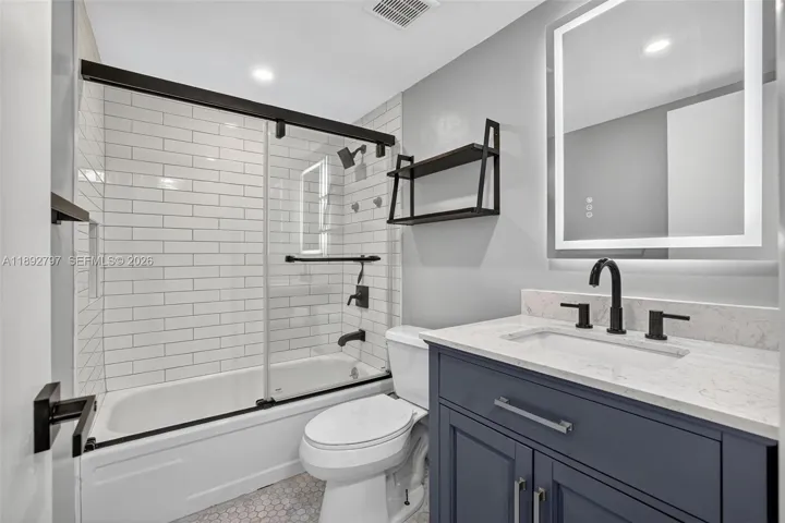 Guest Bathroom w/ glass shower enclosure, combo tub / shower, updated vanity and backlit mirror