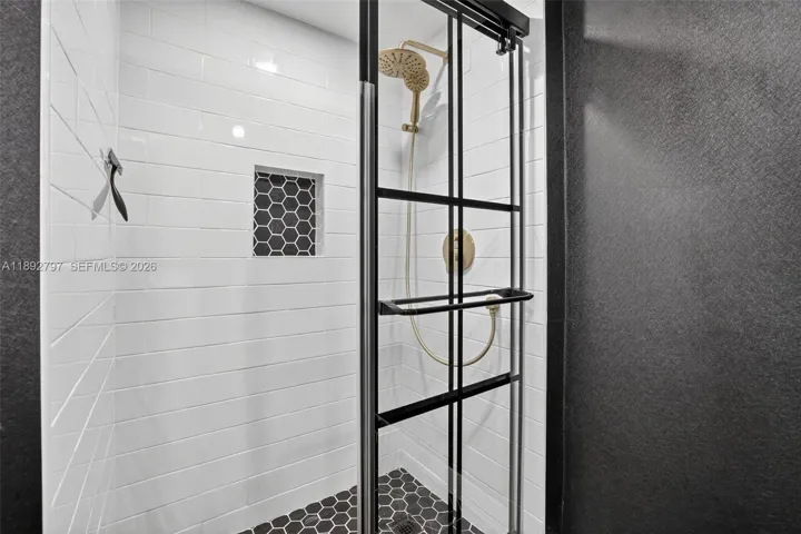 Super cool updated primary bathroom with glass shower enclosure, subway tile, handheld shower head, shampoo niche box