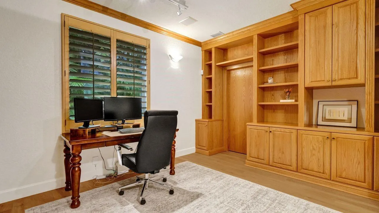 4th Bedroom is a library with floor to ceiling solid wood cabinetry, plantation shutters, generous walk-in closet and adjacent bathroom.