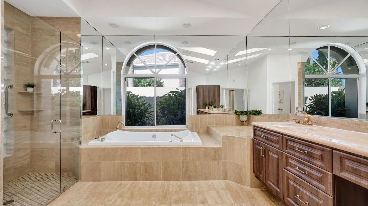 Grand primary bathroom with marble flooring, high-end custom wood cabinetry, seamless glass shower, sep toilet and bidet.
