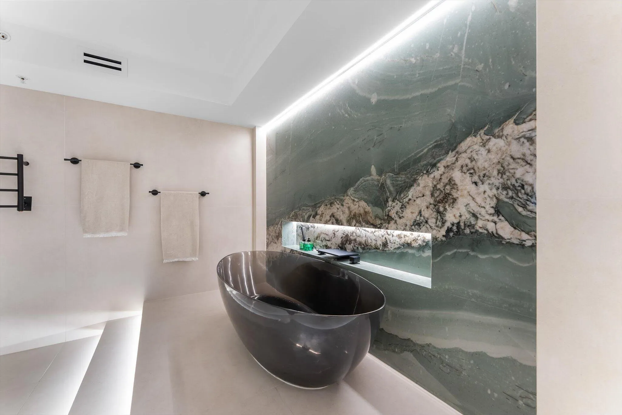 Primary Bathroom of elevated design with Intermare quartzite surfaces, 48x48 imported Spanish tile, and a custom-crafted tub wall that exudes
modern European luxury.