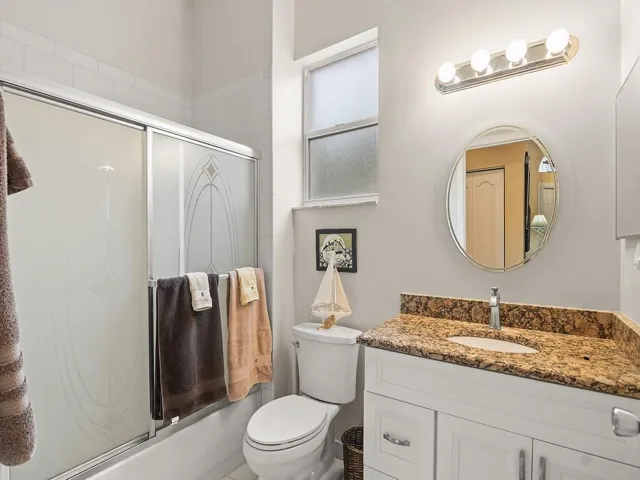 Bathroom featuring vanity and shower / bath combination with glass door
