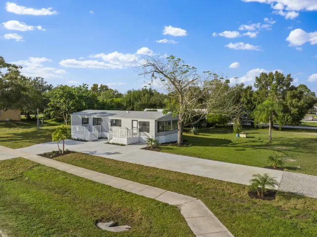 View of front of home featuring a front yard, concrete driveway, and a sunroom