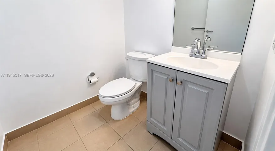 White vanity with a rectangular sink, chrome faucet, and integrated mirror