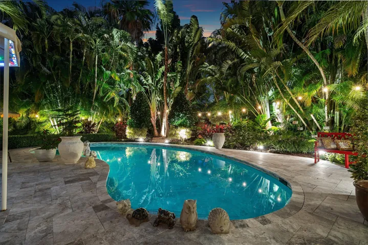 Outdoor patio with large pool and lush landscaping