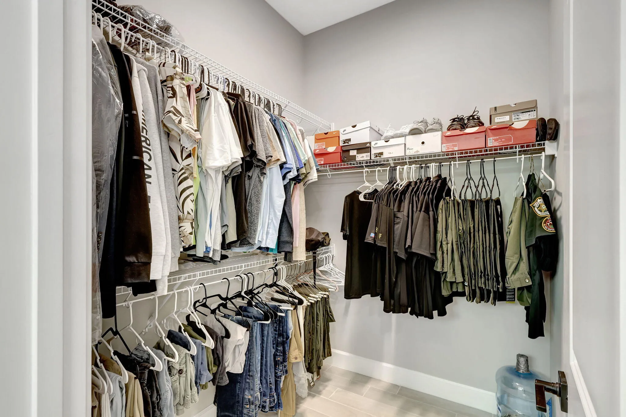 Walk-in closet featuring wire shelving, multiple hanging rods, and light gray walls with white baseboards