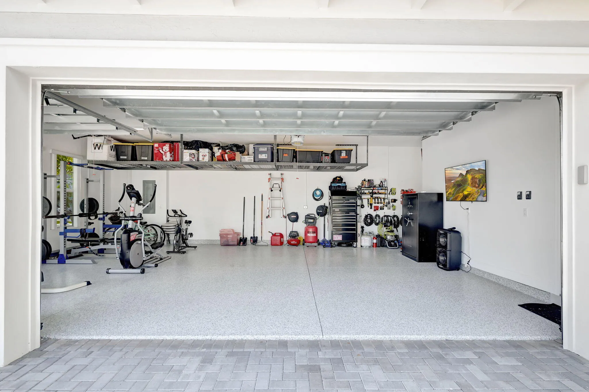 Garage with speckled epoxy flooring, white walls, and overhead storage racks