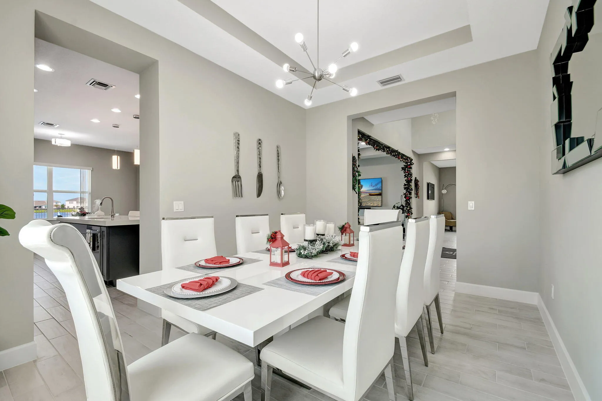 Recessed ceiling with an overhead chandelier, light-toned wood-finish flooring, and a large window providing outdoor visibility