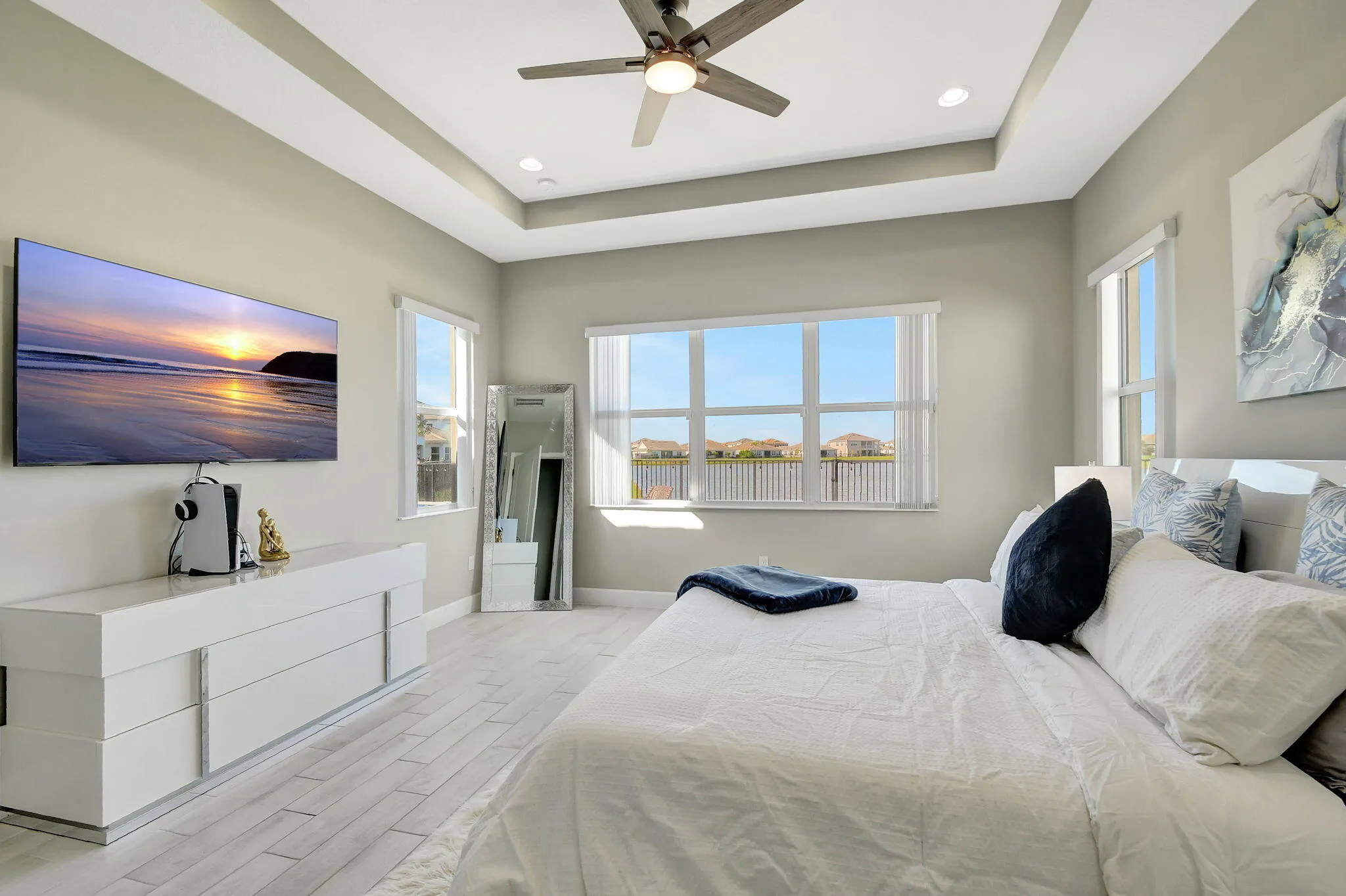 Recessed lighting, ceiling fan, tray ceiling, multiple windows, wood-finish flooring