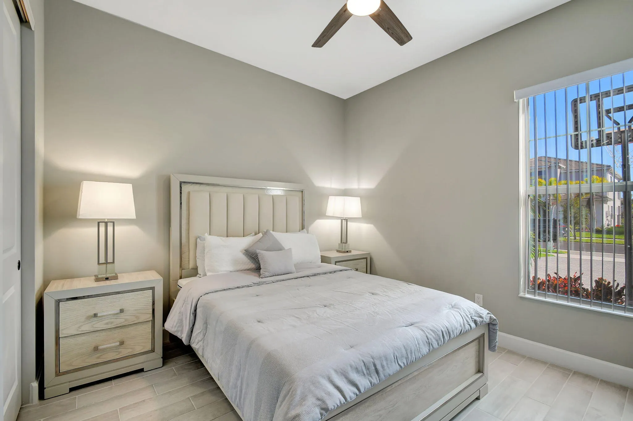 Light-toned wood-finish flooring, ceiling fan with integrated lighting, window with vertical blinds