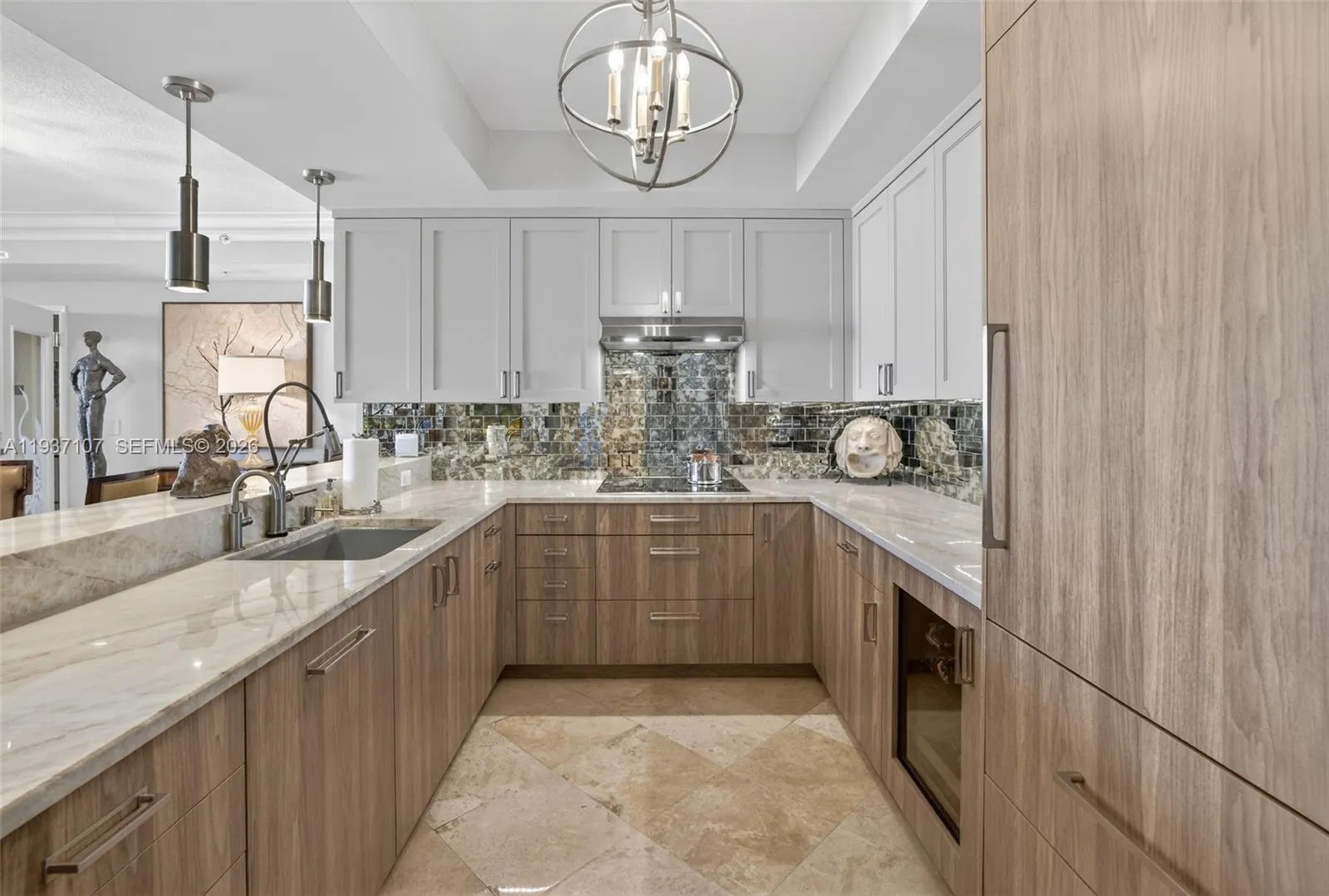 Spectacular kitchen w/ custom bleached walnut veneer cabinetry by renowned Chicago based millworker. Grain matches from top to bottom. Taj mahal quartzite. Wolf induction cooktop & double oven (w/ microwave / convenction at top oven), Sub Zero Refrigerator & Beverage Cooler, Miele Dishwasher. Sink w/ touchless Brizo faucet, including water filtration faucet. Antiqued mirror backsplash. Wide hallway to bedrooms, bathrooms and laundry room. through archway