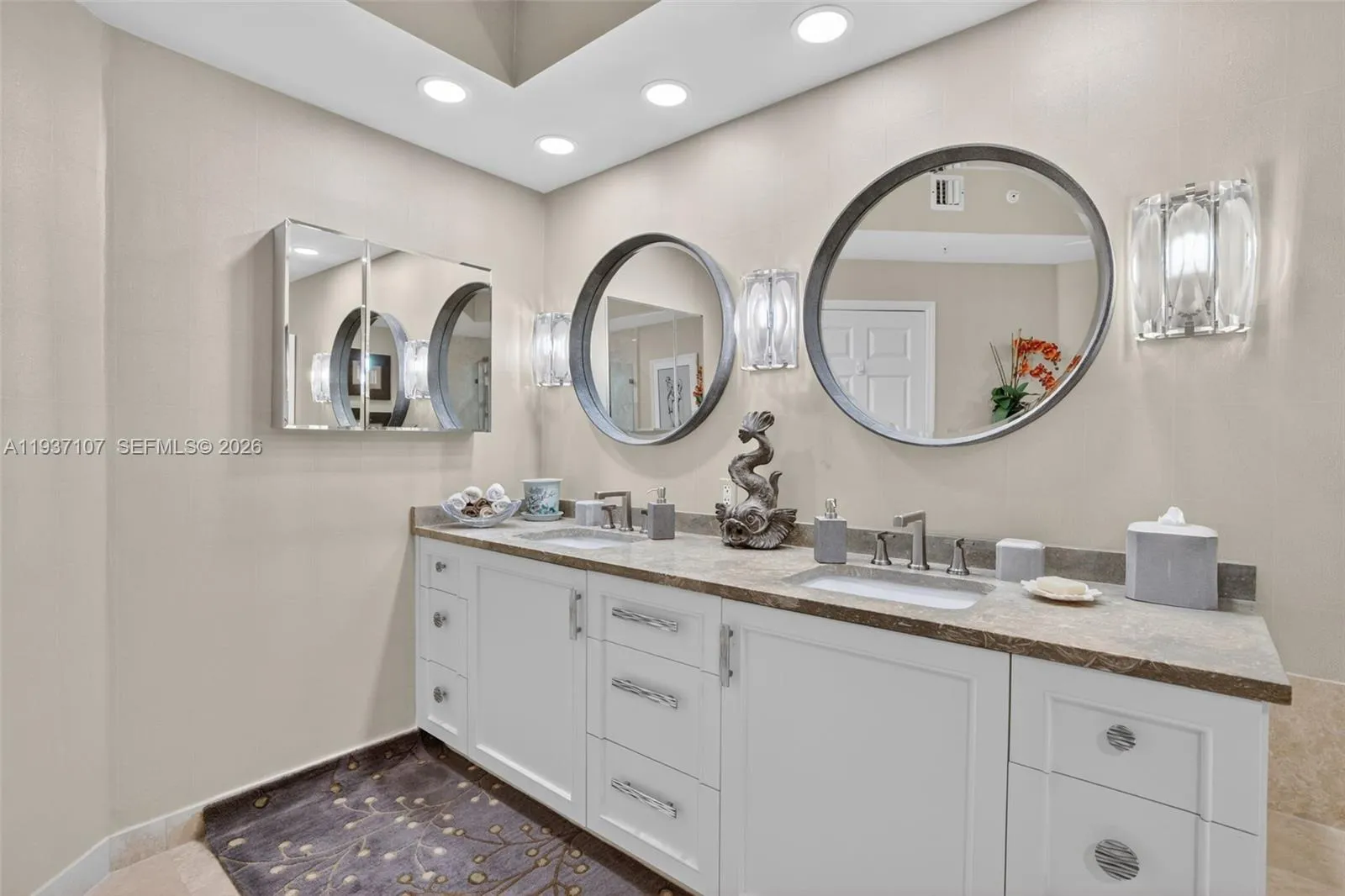 Primary bathroom w/ custom wood vanity & upgraded hardware. Beautiful stone vanity counter, wall coverings, sconces, separate medicine cabinet and mirrors.