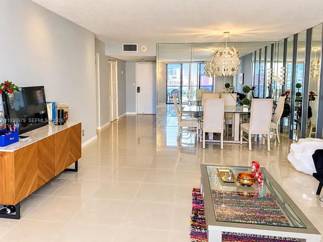 Open-concept floor plan featuring large-format ceramic tile flooring, full-height wall mirrors, and an integrated hanging pendant light fixture