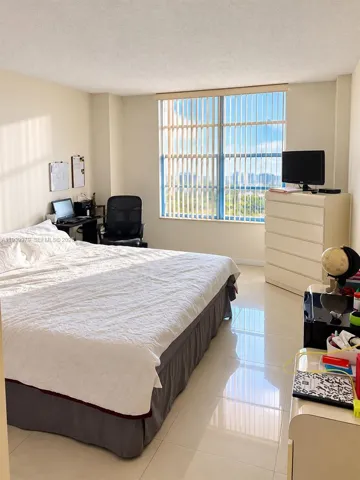 Expansive room with large-format tile flooring and floor-to-ceiling windows featuring vertical blinds and an outdoor urban landscape