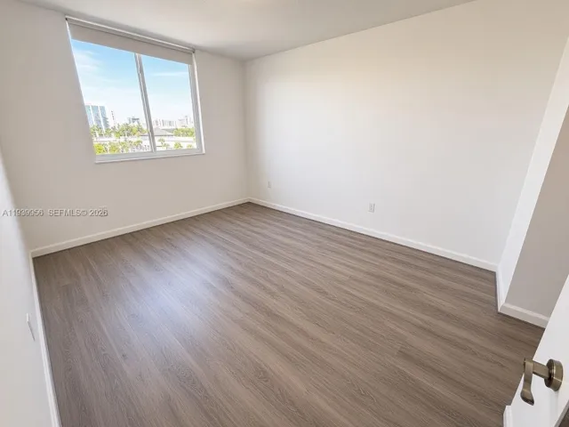 Room featuring wood-finish flooring, neutral walls, and a large window with exterior scenery