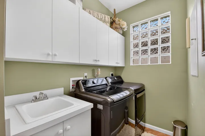 Full laundry with sink and cabinets for storage plus there is a utility closet.