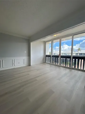 Balcony/ Florida Room/ Office space connected to Living/ Family room. Sliding doors were removed to connect the space for more usage. Window treatments / dividers can be added to separate the rooms.Brand new flooring just installed. Custom moldings (wainscoting) / wood work throughout the unit. View from balcony/ patio/ sun room looks over the St. Lucie River, pier, club house, pool, and shuffle board.