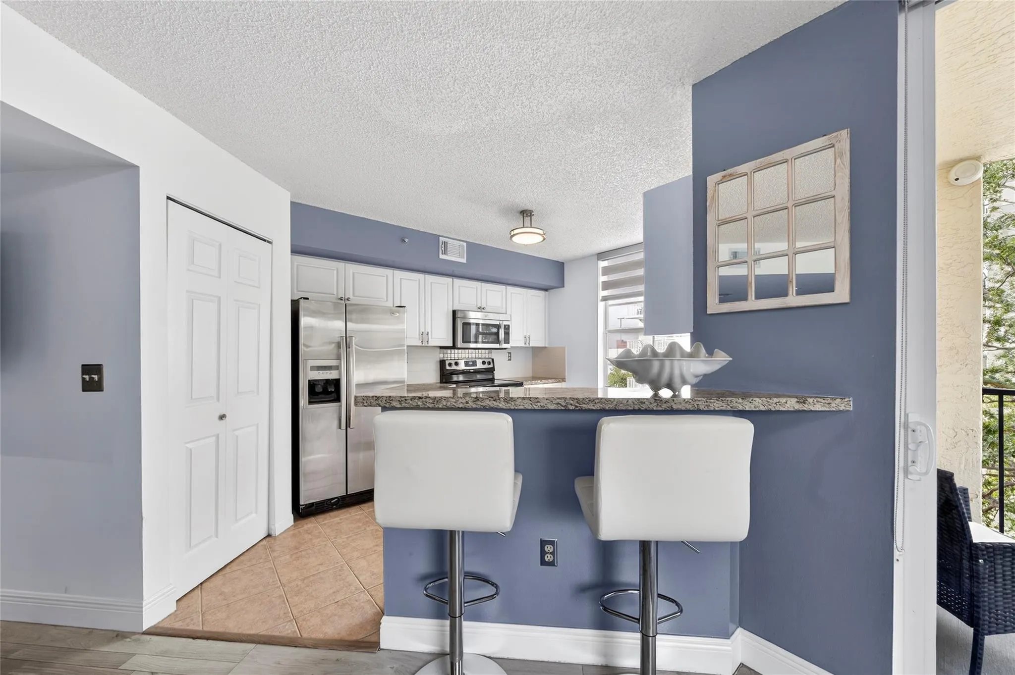 Updated kitchen features stainless steel appliances, granite countertops, and a custom tile backsplash, seamlessly connected to the living space and breakfast bar for easy everyday living and entertaining.