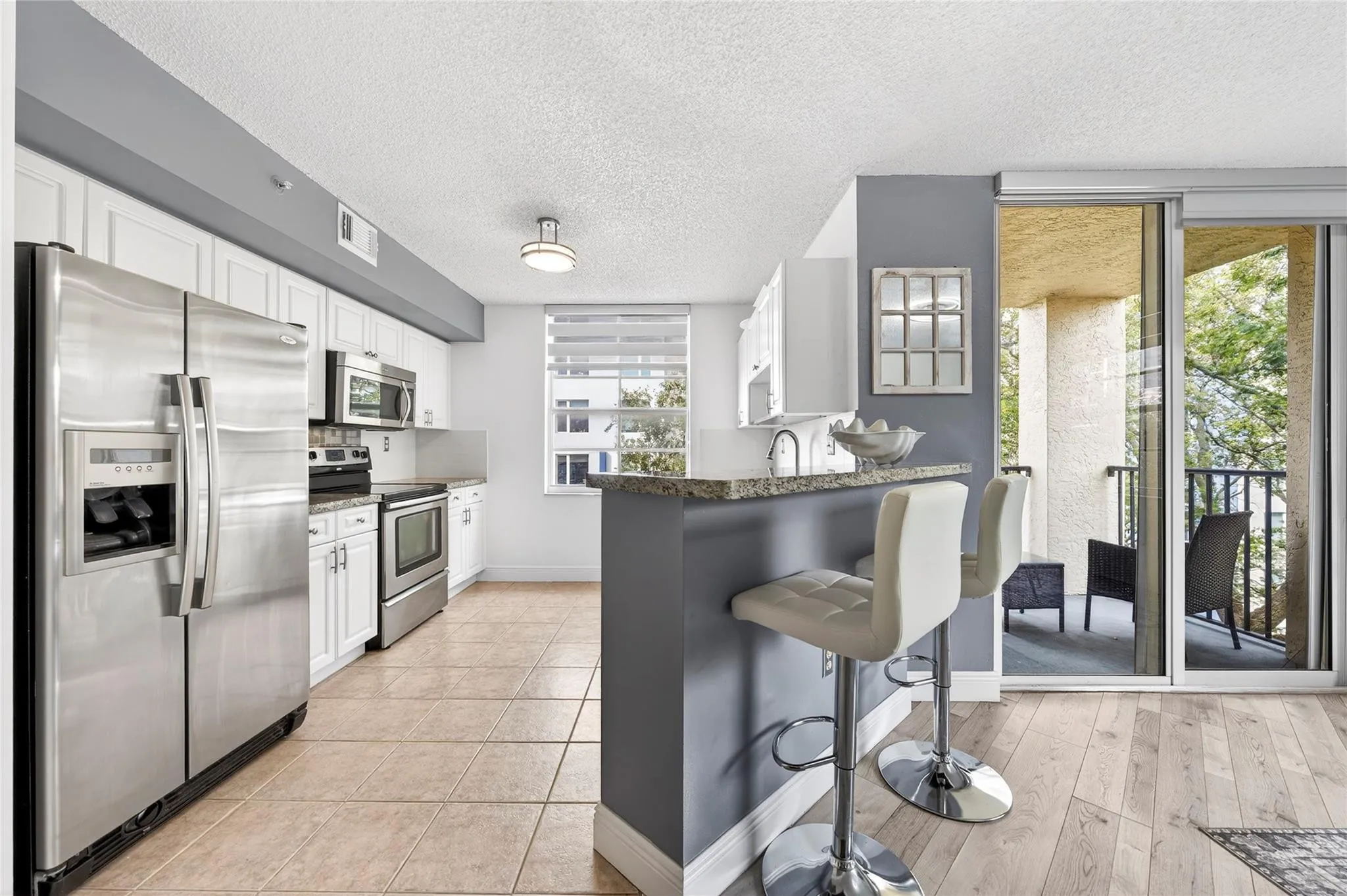 Updated kitchen features stainless steel appliances, granite countertops, and a custom tile backsplash, seamlessly connected to the living space and breakfast bar for easy everyday living and entertaining.