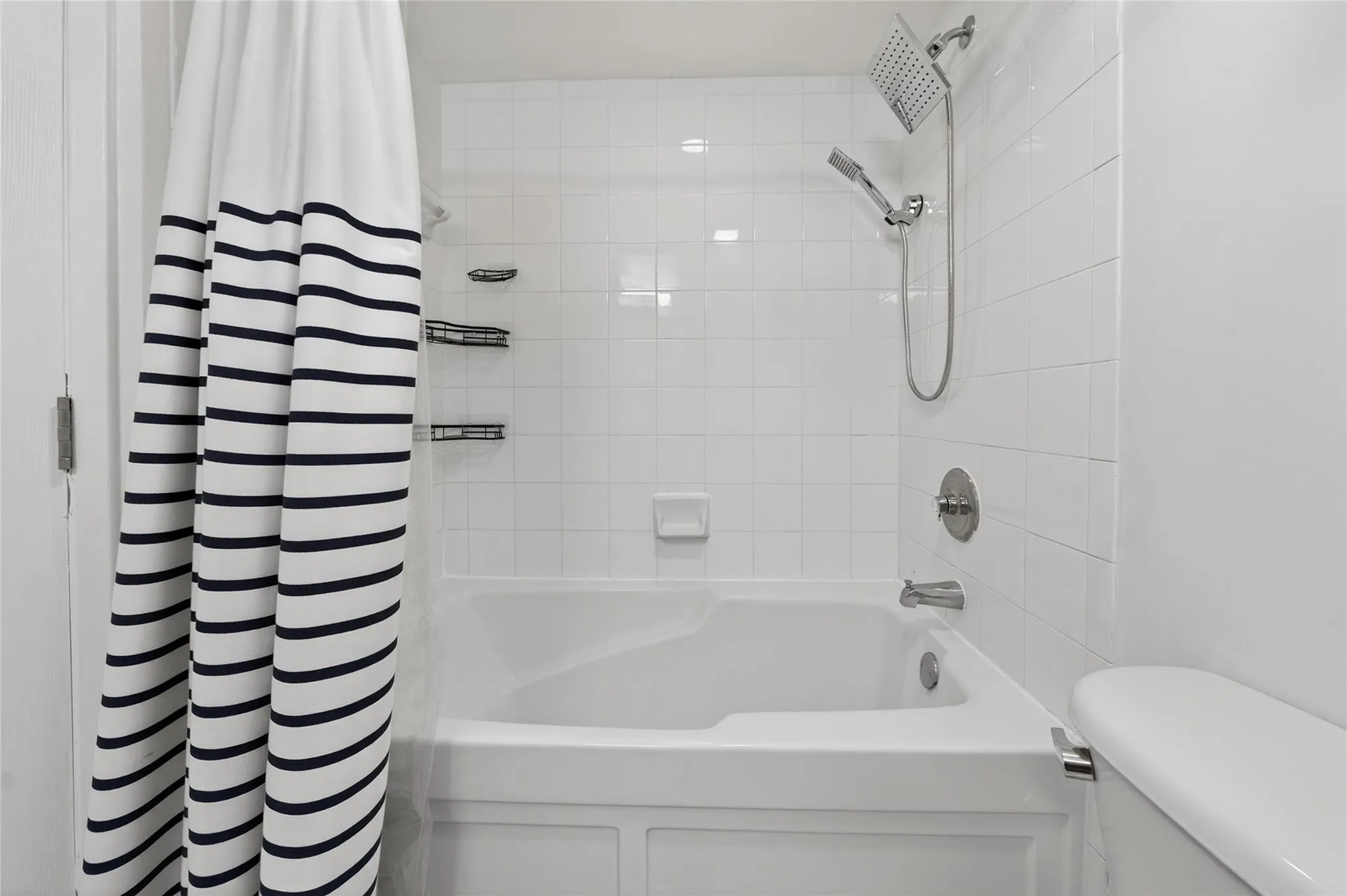 Secondary bathroom features a new vanity and a full tub with clean tile surround and updated fixtures